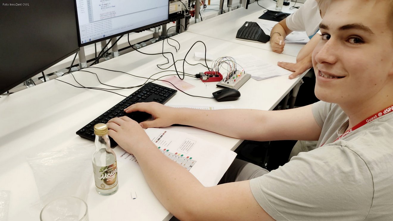 Lächelnder Workshop-Teilnehmer bei dSPACE arbeitet an einer Elektronikschaltung mit Breadboard und LEDs